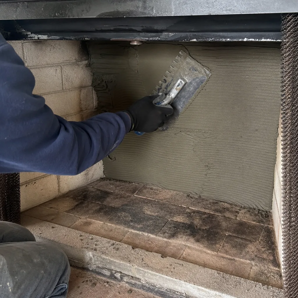 Professional technician applying mortar to fireplace wall for renovation